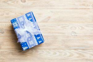 paper gift box with colored ribbon on orange wood background. top view with copy space Christmas holiday concept photo