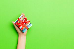 Top view of female hands holding christmas or other holiday handmade present box package in the palms, flat lay table background with copy space photo