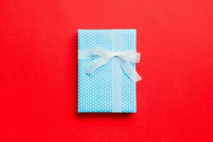 Top view Christmas present box with white bow on red background with copy space photo