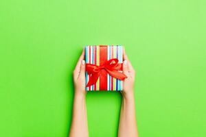 Top view of female hands holding christmas or other holiday handmade present box package in the palms, flat lay table background with copy space photo