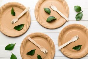 set of empty reusable disposable eco-friendly plates, cups, utensils on light white colored table background. top view. Biodegradable craft dishes. Recycling concept. Close-up photo