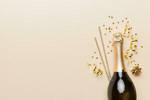 bottle of champagne with glasses and colorful confetti on colored background. top view flay lay photo