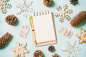 Top view of notebook, holiday toys and decorations on blue Christmas background. New Year time concept photo