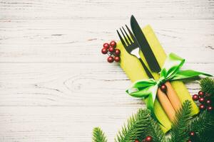 Top view of christmas decorations on wooden background. Fork and knife on napkin tied up with ribbon and empty space for your design. New year pattern concept photo