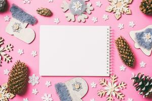 Top view of notebook, holiday toys and decorations on pink Christmas background. New Year time concept photo