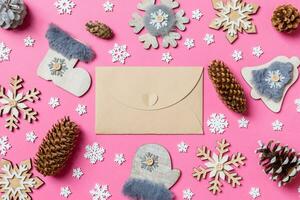 Top view of craft envelope, holiday toys and decorations on pink Christmas background. New Year time concept photo