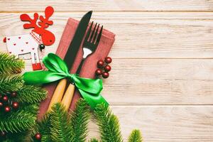Top view of flatware tied up with ribbon on napkin on wooden background. Christmas decorations and reindeer with empty space for your design. New Year holiday concept photo