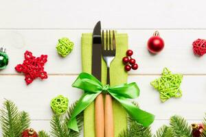 Top view of christmas decorations on wooden background. Fork and knife on napkin tied up with ribbon and empty space for your design. New year pattern concept photo