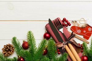 Top view of christmas decorations on wooden background. Fork and knife on napkin tied up with ribbon and empty space for your design. New year pattern concept photo