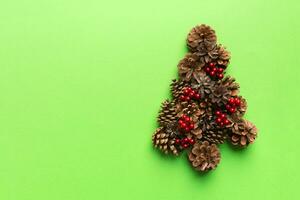 Christmas tree made from natural cones on colored background, view from above. New Year minimal concept with copy space photo