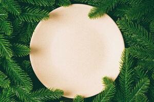 Top view of round festive plate on fir tree background. Christmas dish concept with empty space for your design photo