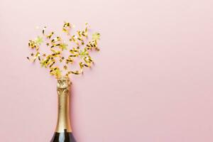 Creative flat lay composition with bottle of champagne and space for text on color background. Champagne bottle with colorful party streamers. holiday or christmas concept photo