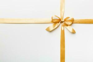 Top view of gold ribbon rolled and yellowbow isolated on colored background. Flat lay with copy space photo