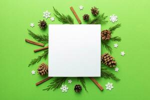 Flat lay Christmas composition. square Paper blank, pine tree branches, christmas decorations on Colored background. Top view, copy space for text photo