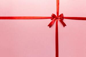 Top view of Red ribbon rolled and red bow isolated on colored background. Flat lay with copy space photo