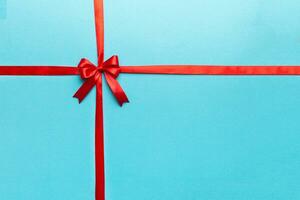 Top view of Red ribbon rolled and red bow isolated on colored background. Flat lay with copy space photo