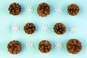 Top view of holiday composition made of pine cones and white snowflakes on colorful background. Winter time and Christmas concept with copy space photo