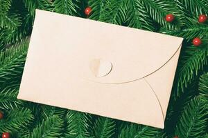 Top view of envelope decorated with a frame made of fir tree on wooden background. New Year time concept photo