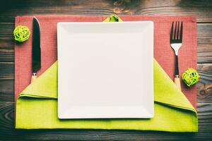 Top view of New Year dinner on festive wooden background. Composition of plate, fork, knife, fir tree and decorations. Merry Christmas concept photo