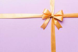 Top view of gold ribbon rolled and yellowbow isolated on colored background. Flat lay with copy space photo