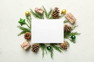 Flat lay Christmas composition. square Paper blank, pine tree branches, christmas decorations on Colored background. Top view, copy space for text photo