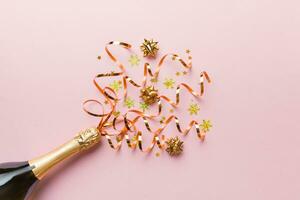 Creative flat lay composition with bottle of champagne and space for text on color background. Champagne bottle with colorful party streamers. holiday or christmas concept photo