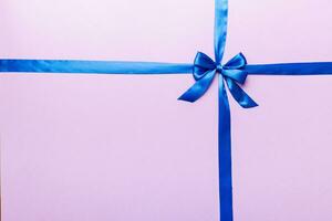 Top view of blue ribbon rolled and blue bow isolated on colored background. Flat lay with copy space photo