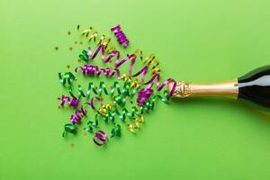 Creative flat lay composition with bottle of champagne and space for text on color background. Champagne bottle with colorful party streamers. holiday or christmas concept photo