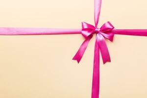 Top view of purple ribbon rolled and pink bow isolated on colored background. Flat lay with copy space photo