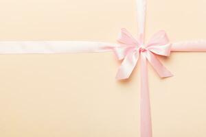 Top view of purple ribbon rolled and pink bow isolated on colored background. Flat lay with copy space photo