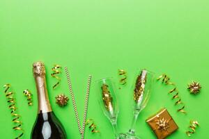 Bottle of champagne with colored glitter, confetti and gift box space for text on colorfull background, top view. Hilarious, christmas and birthday celebration photo