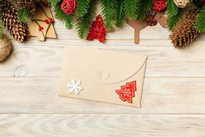 Top view of envelope, Christmas toys, decorations and fir tree branches on wooden background. New Year holiday concept photo