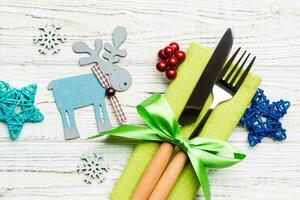 New year set of fork and knife on napkin. Top view of christmas decorations and reindeer on wooden background. Close up of holiday family dinner concept photo