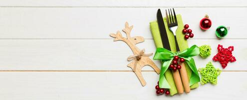 New year set Banner of fork and knife on napkin. Top view of christmas decorations and reindeer on wooden background. Holiday family dinner concept with empty space for your design photo
