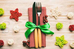 Top view of holiday set of fork and knife on wooden background. Close up of Christmas decorations and toys. New Year Eve concept photo