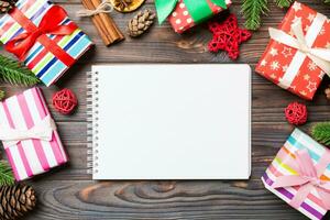 Top view of a notebook on wooden holiday background made of fir tree and New Year decorations. Christmas time concept photo