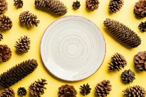 Top view of festive plate with pine cones on colorful background. New Year dinner concept photo