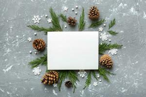 Flat lay Christmas composition. square Paper blank, pine tree branches, christmas decorations on Colored background. Top view, copy space for text photo