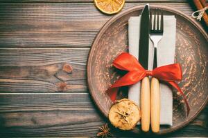 Top view of holiday dinner decorated with dried fruit and cinnamon on wooden background. Set of plate, urensil and New Year decorations. Christmas time concept with epmty space for your design photo