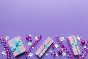 Holiday flat lay with gift boxes wrapped in colorful paper and tied decorated with confetti on colored background. Christmas, Birthday, Valentine and sale concept, top view photo