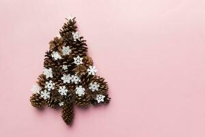 Christmas tree made from natural cones on colored background, view from above. New Year minimal concept with copy space photo