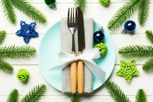 Top view of New Year dinner on festive wooden background. Composition of plate, fork, knife, fir tree and decorations. Merry Christmas concept photo