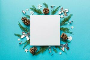 Flat lay Christmas composition. square Paper blank, pine tree branches, christmas decorations on Colored background. Top view, copy space for text photo