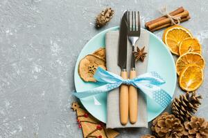 Top view of holiday dinner decorated with dried fruit and cinnamon on cement background. Set of plate, urensil and New Year decorations. Christmas time concept with epmty space for your design photo