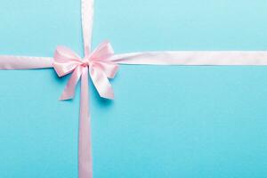 Top view of purple ribbon rolled and pink bow isolated on colored background. Flat lay with copy space photo