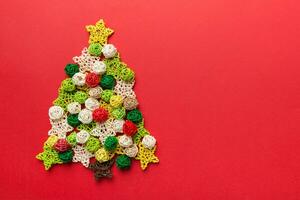 Christmas tree made from colored handmade ball decoration on colored background, view from above. New Year minimal concept with copy space photo
