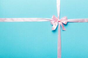 Top view of purple ribbon rolled and pink bow isolated on colored background. Flat lay with copy space photo