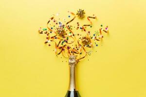 Creative flat lay composition with bottle of champagne and space for text on color background. Champagne bottle with colorful party streamers. holiday or christmas concept photo