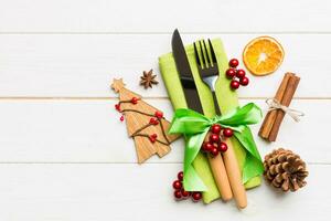 Top view of utensils on festive napkin on wooden background. Christmas decorations with dried fruits and cinnamon. New year dinner concept with copy space photo