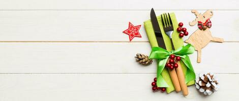 New year set of Banner fork and knife on napkin. Top view of christmas decorations and reindeer on wooden background. Holiday family dinner concept with empty space for your design photo